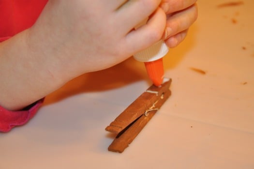 child putting glue on clothespin