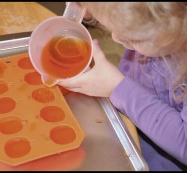 girl pouring into pumpkin ice cube tray