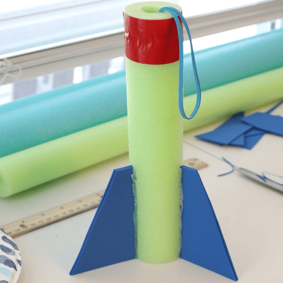 Pool Noodle Activities- rocket green blue and red with rubber band - Kids Activities Blog