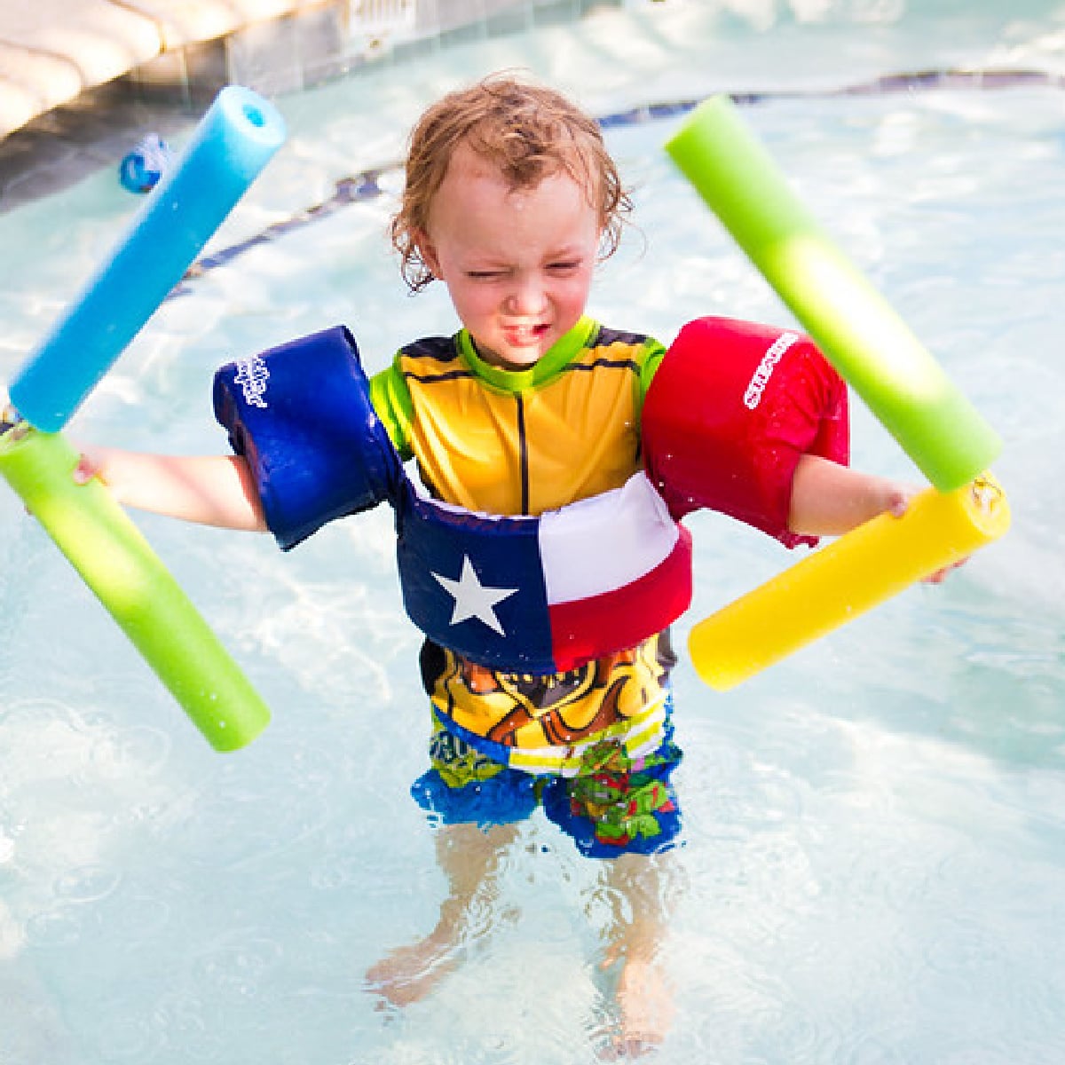Pool Noodle Activities- boy holding pool noodle nunchucks in floaties - Kids Activities Blog