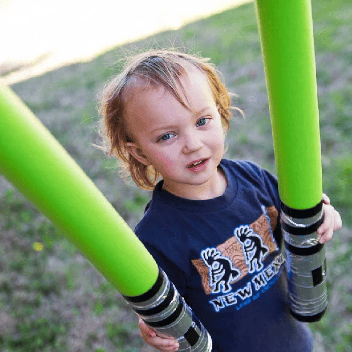 Pool Noodle Activities- boy holding two noodles that look like lightsabers- Kids Activities Blog