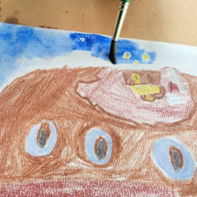boy painting blue watercolor paint over underwater scene - kids activities blog