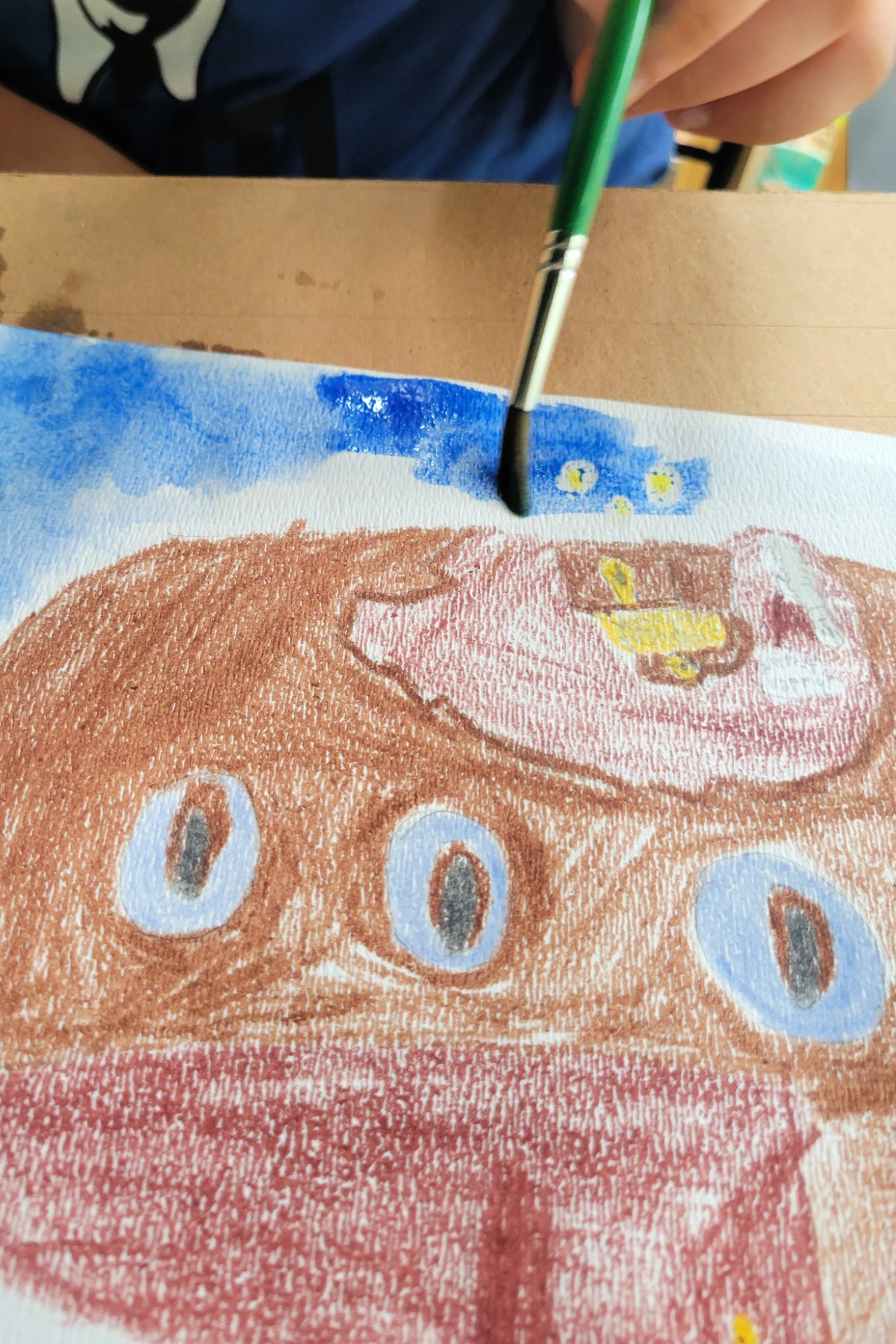 Boy painting underwater scene using watercolor paint and wax resist - Kids Activities Blog