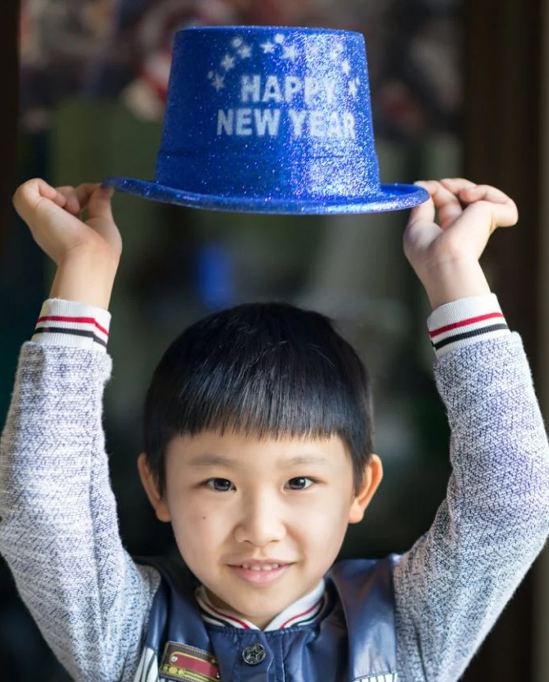 A young kid with a hat that says happy new year.