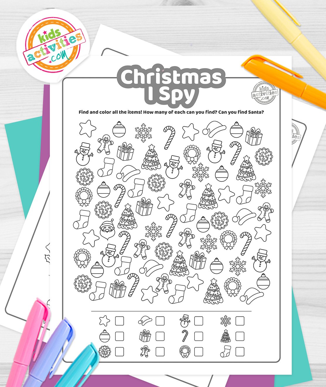 Stack of printed Christmas I Spy printables on top of green and purple pages, with markers next to them, on top of a gray background.