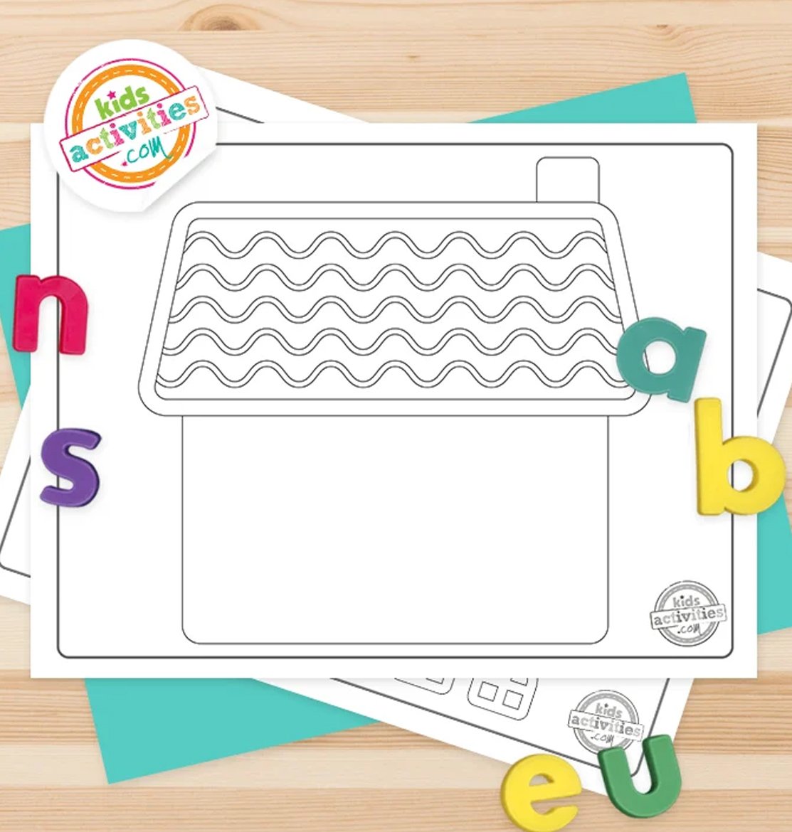 Stack of printed gingerbread house printables on top of green and purple pages, with markers next to them, on top of a brown background.