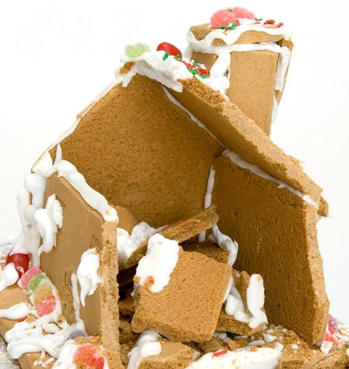 A gingerbread house in the process of being built with homemade icing.