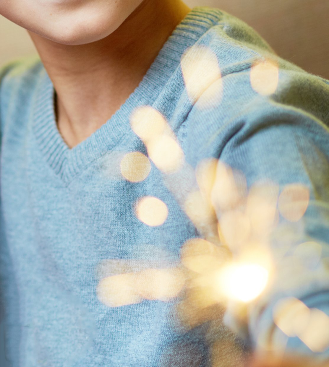 A closeup of a kid holding a sparkling firework.