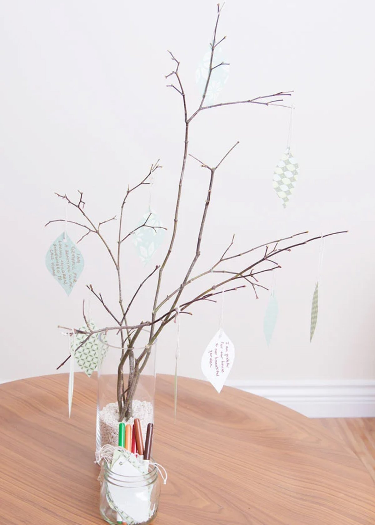 A gratitude tree made with small tree branches and pieces of paper with positive phrases about gratitude.