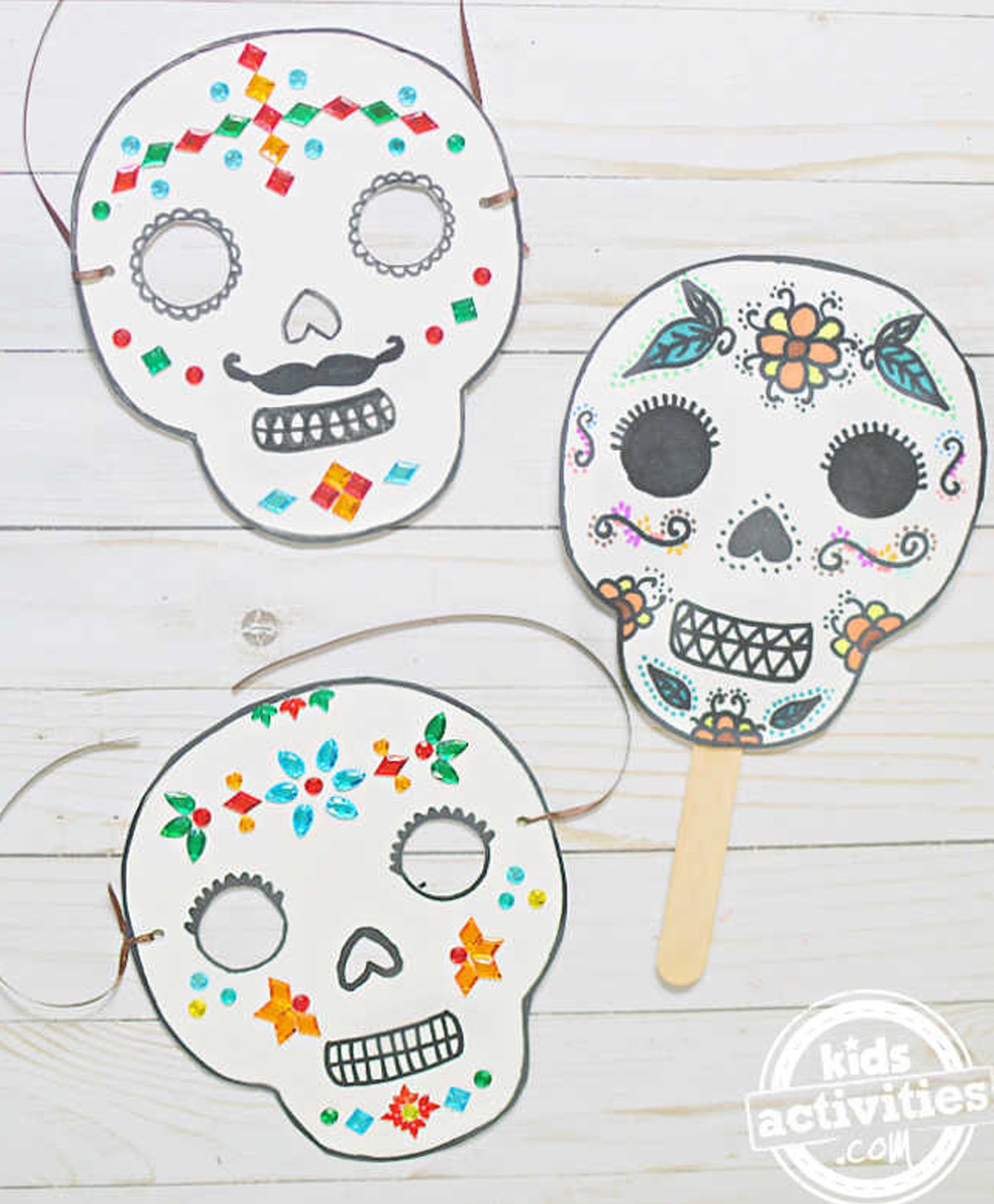 Three day of the dead-inspired masks on top of a gray background.