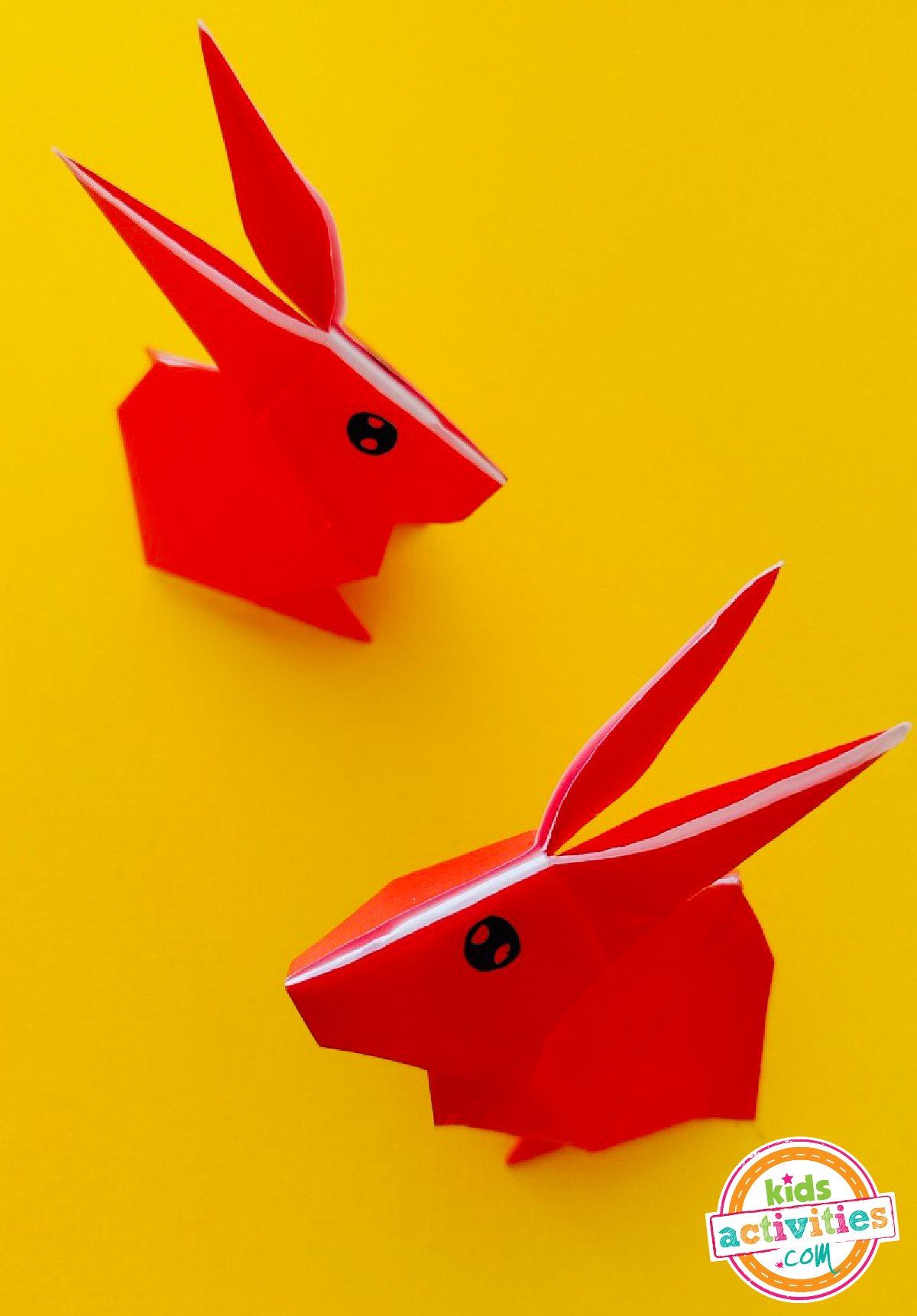 Finished result of a bunny origami on top of yellow paper.