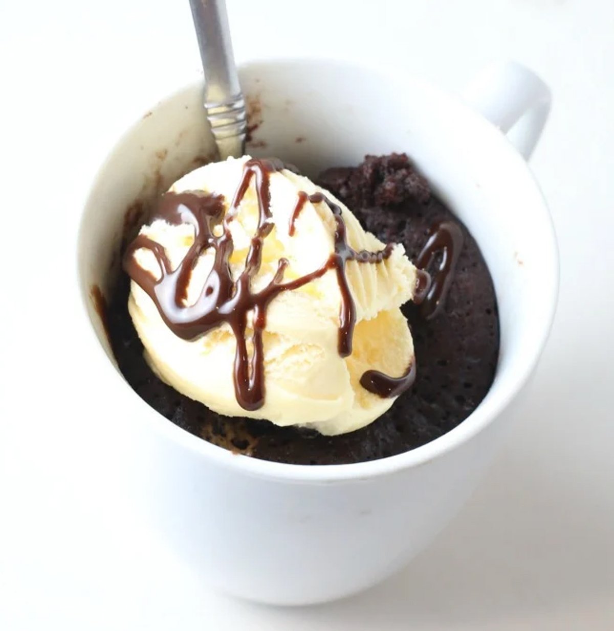 A chocolate lava mug cake with ice cream on top.