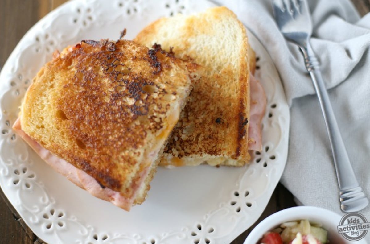 A grilled sandwich with ham and cheese cut in half.