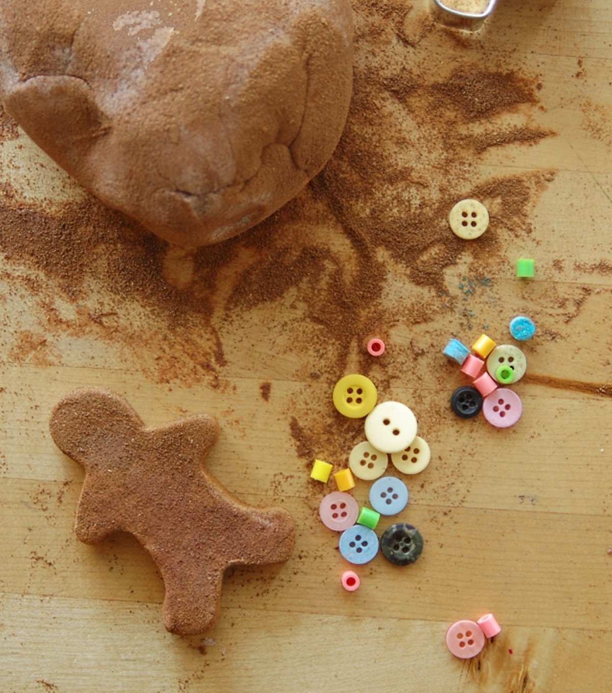 A playdough gingerbread man with crafting supplies like colored buttons.