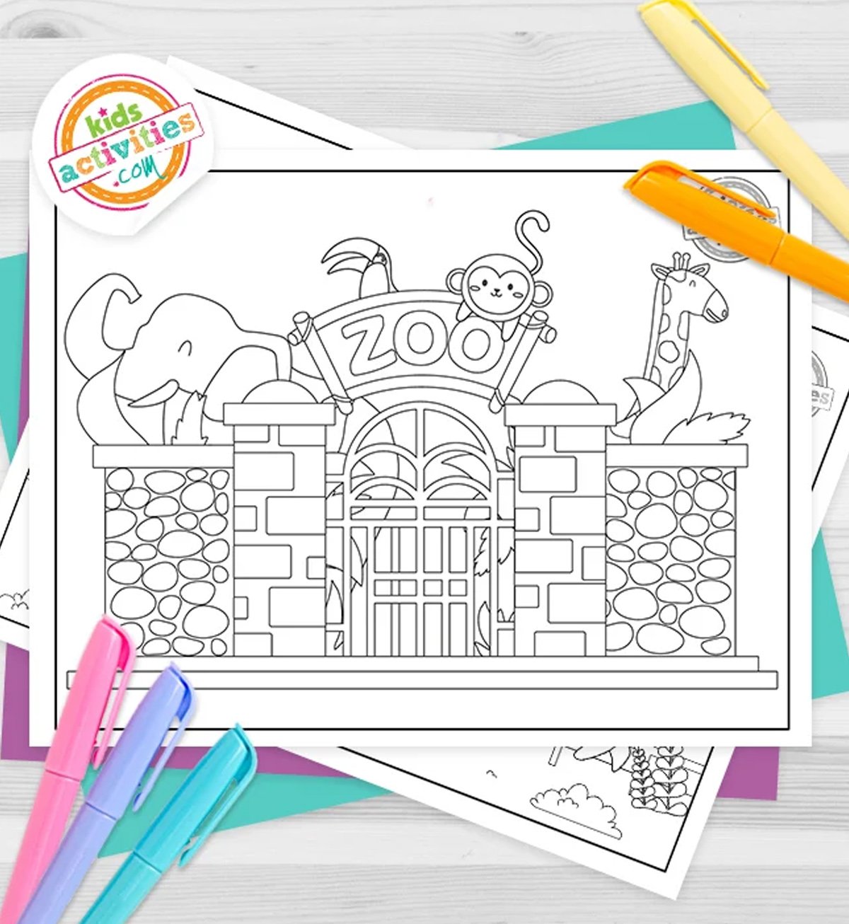 Black and white Zoo coloring pages lying on top of blue-green and purple sheets with assorted crayons on a gray background.