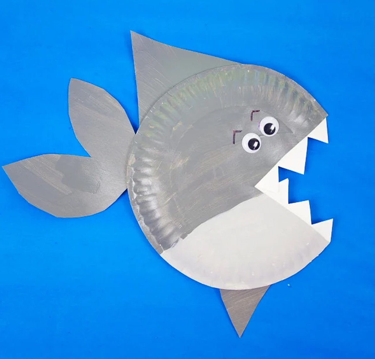 A shark paper plate craft on top of a blue background.
