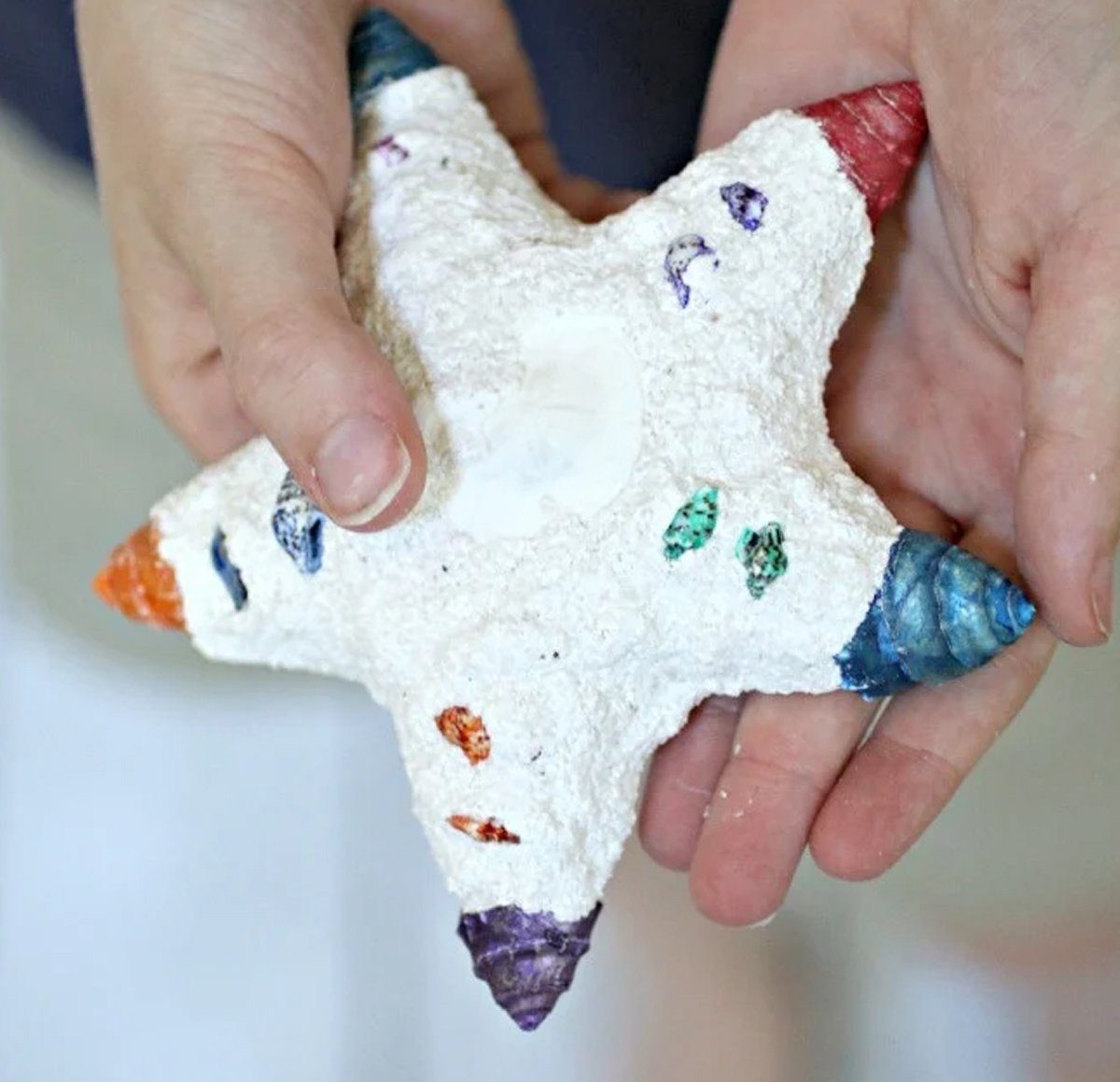 A kid holding a handmade sand and plaster star.