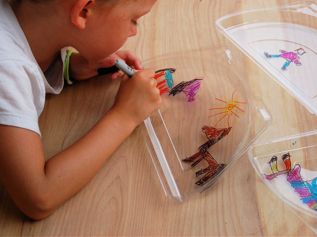 Layered Art- Step 1- Boys coloring pictures on a plastic lid- kids activities blog
