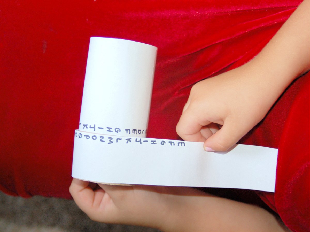 Coded Message Craft- child wrapping paper around a toilet paper roll with the alphabet- kids activities blog
