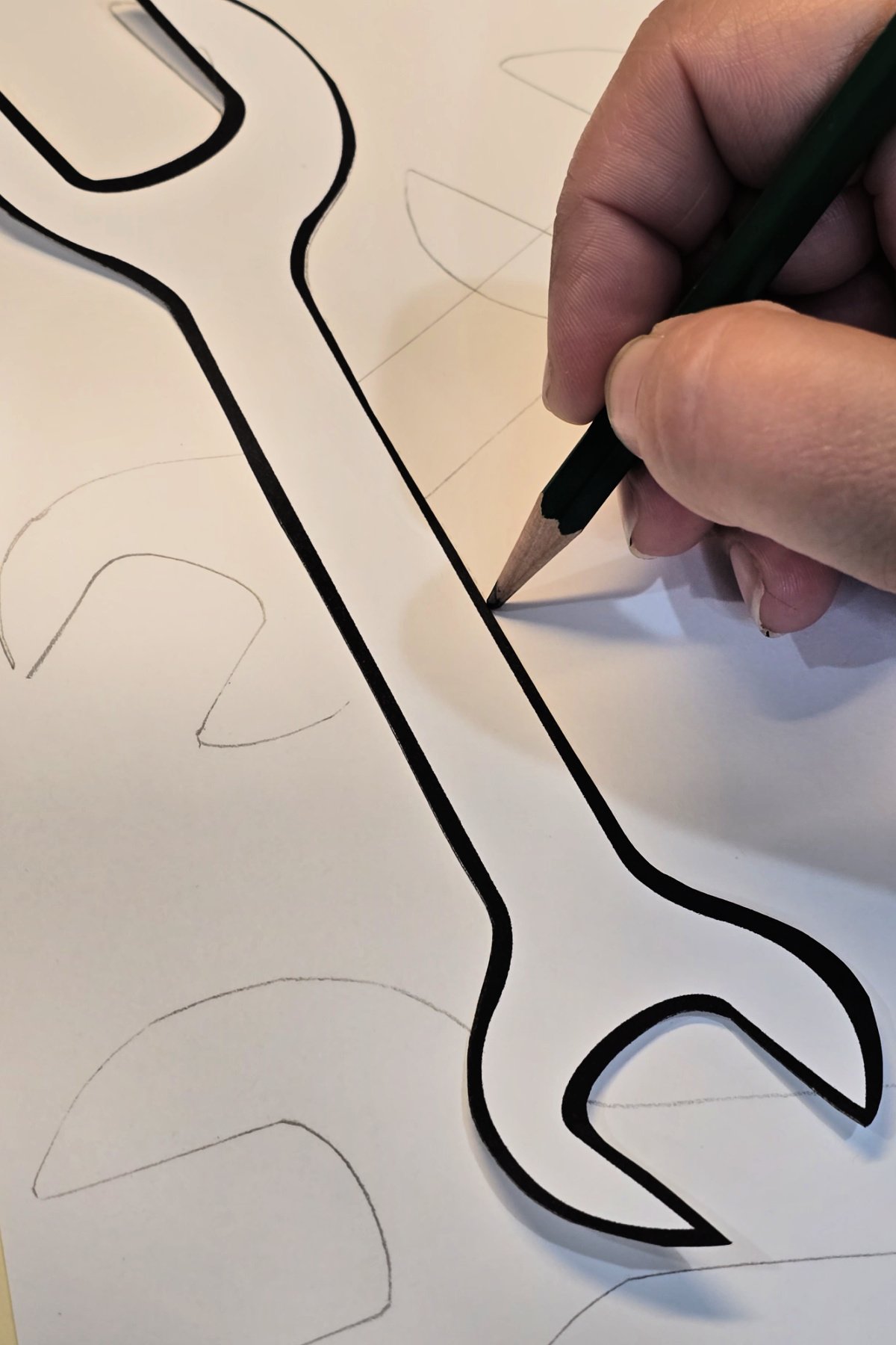 step 2 - using a pencil to trace wrench shapes overlapping on cardstock - kids activities blog