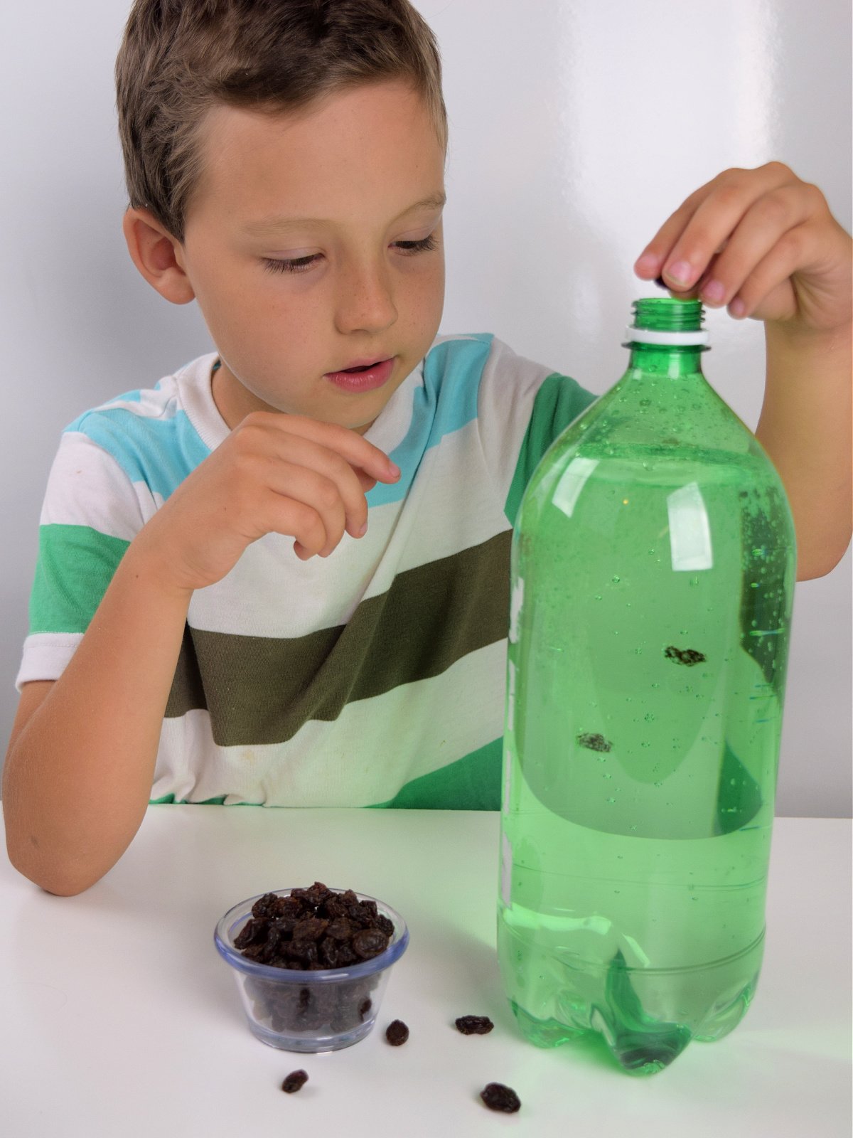 Dancing Raisins- Step 2- Put raisins in the bottle by a little boy- Kids Activities Blog