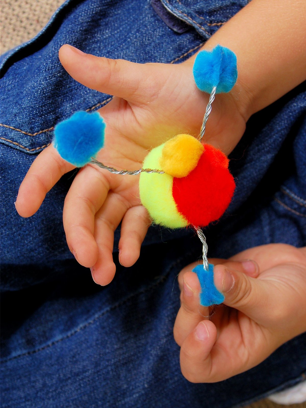 Make an atom- finished atom with blue, red, orange pom poms- kids activities blog