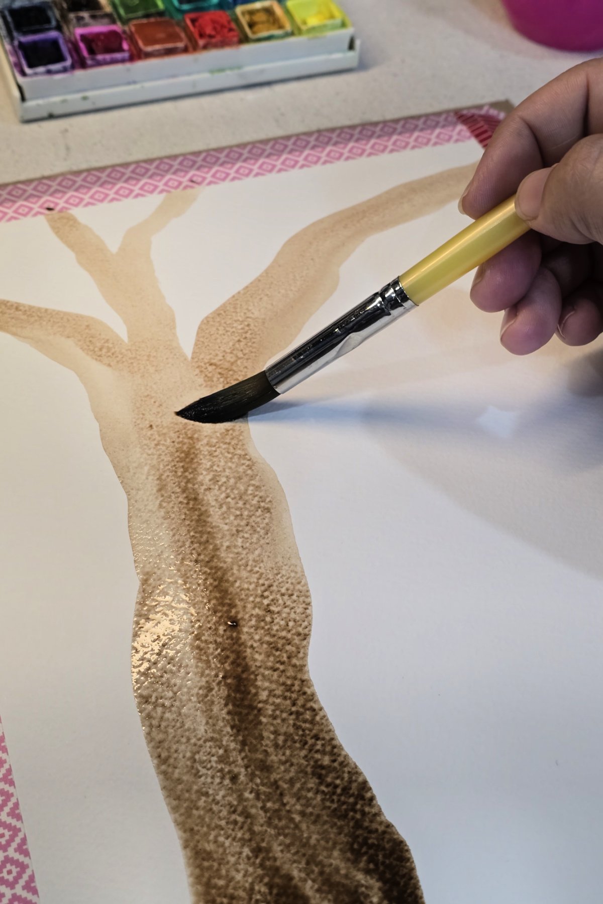 step 2 - using brown watercolor paint to paint a tree trunk and branches on watercolor paper - kids activities blog