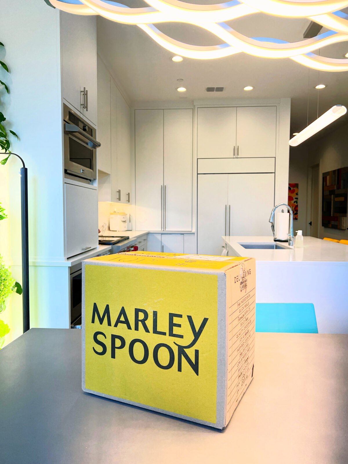 Marley Spoon subscription meal box on kitchen table in kitchen with white cabinets and counter tops