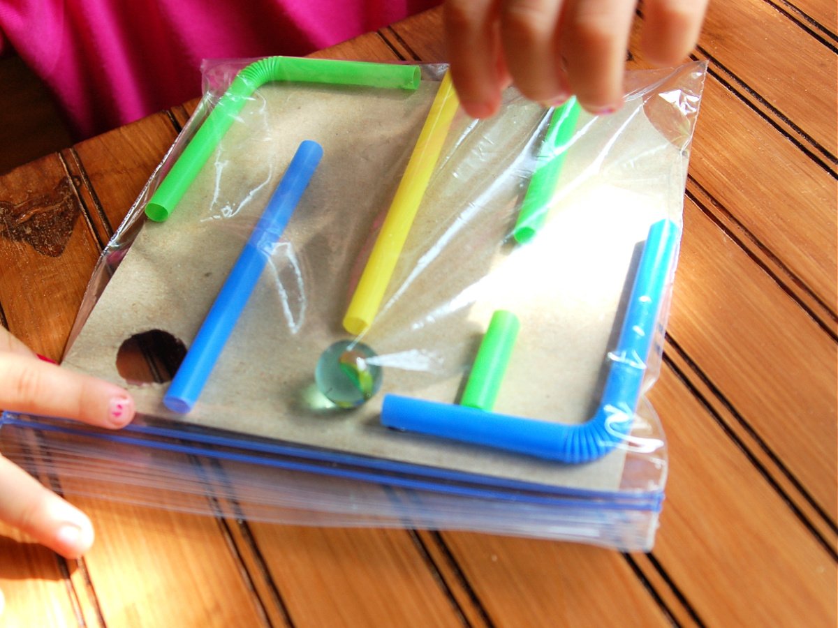 Maze Craft- Step 4 - Child playing with marble maze in baggie - Kids Activities Blog