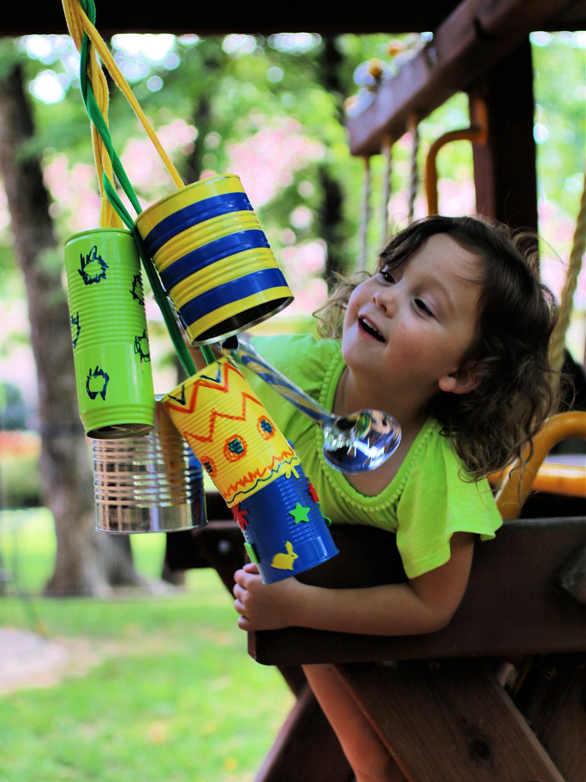 Homemade wind chimes craft- child smacking the wind chimes in a play set with a metal spoon- kids activities blog