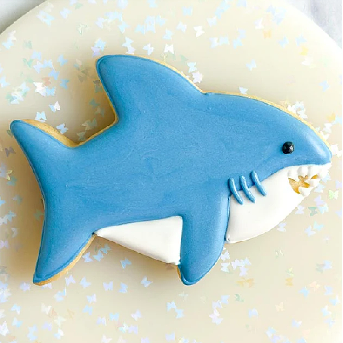Shark Week- decorated sugar cookie to look like a shark on a sparkly background- kids activities blog