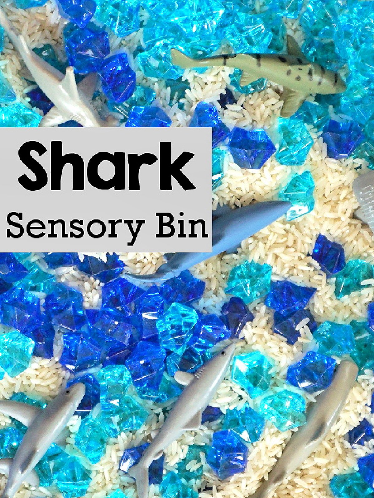 Shark Sensory Bin- Rice, sharks, and light and dark blue faux gems- kids activities blog