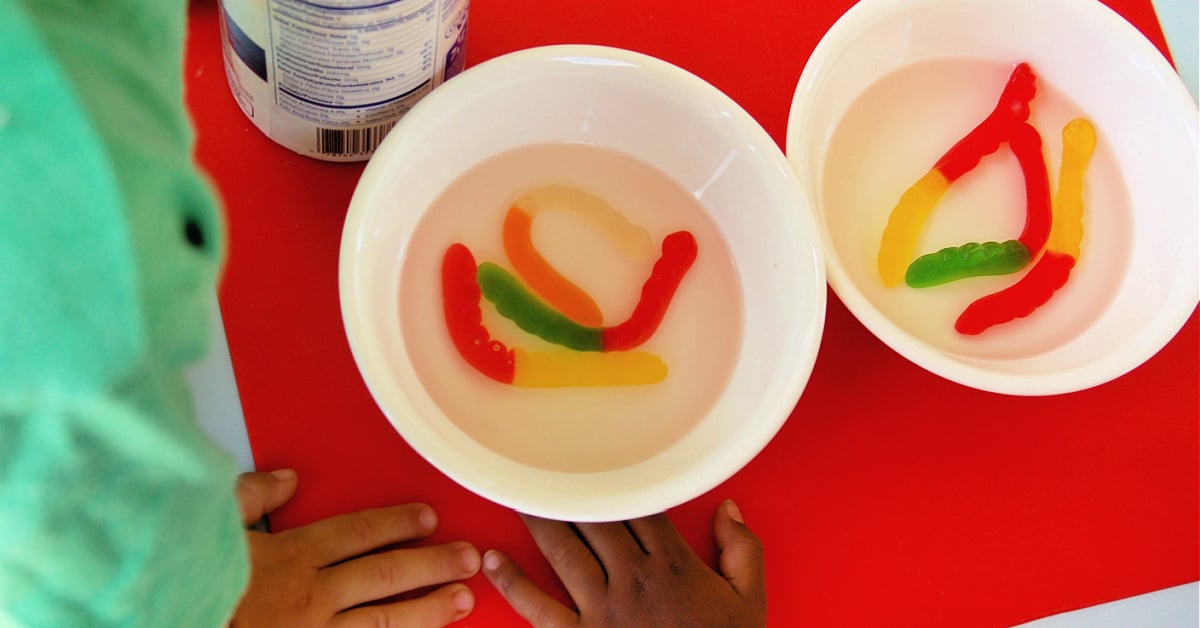 Growing Gummies- 2 bowls of gummy worms with 2 children and a red background- kids activities blog