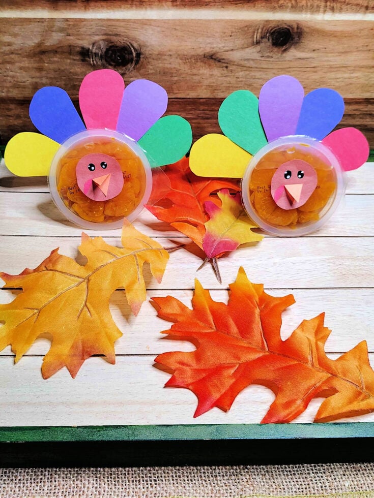 Completed turkey craft with oranges, paper feathers, and leaves.