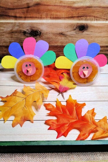 Turkeys made from orange cups with simple thanksgiving craft with leaves and wood background- kids activities blog