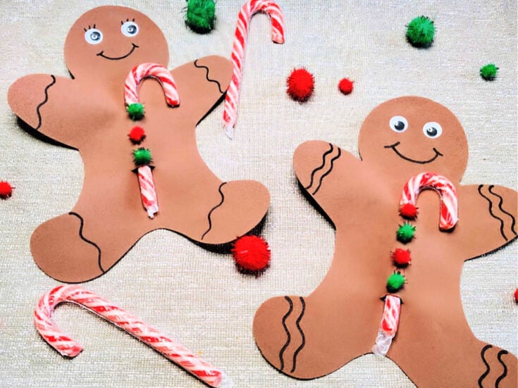 Candy Cane Holder Craft- Finished - Gingerbread man and woman with candy cane surrounded with pom poms and candy canes on silver background - Kids Activities Blog
