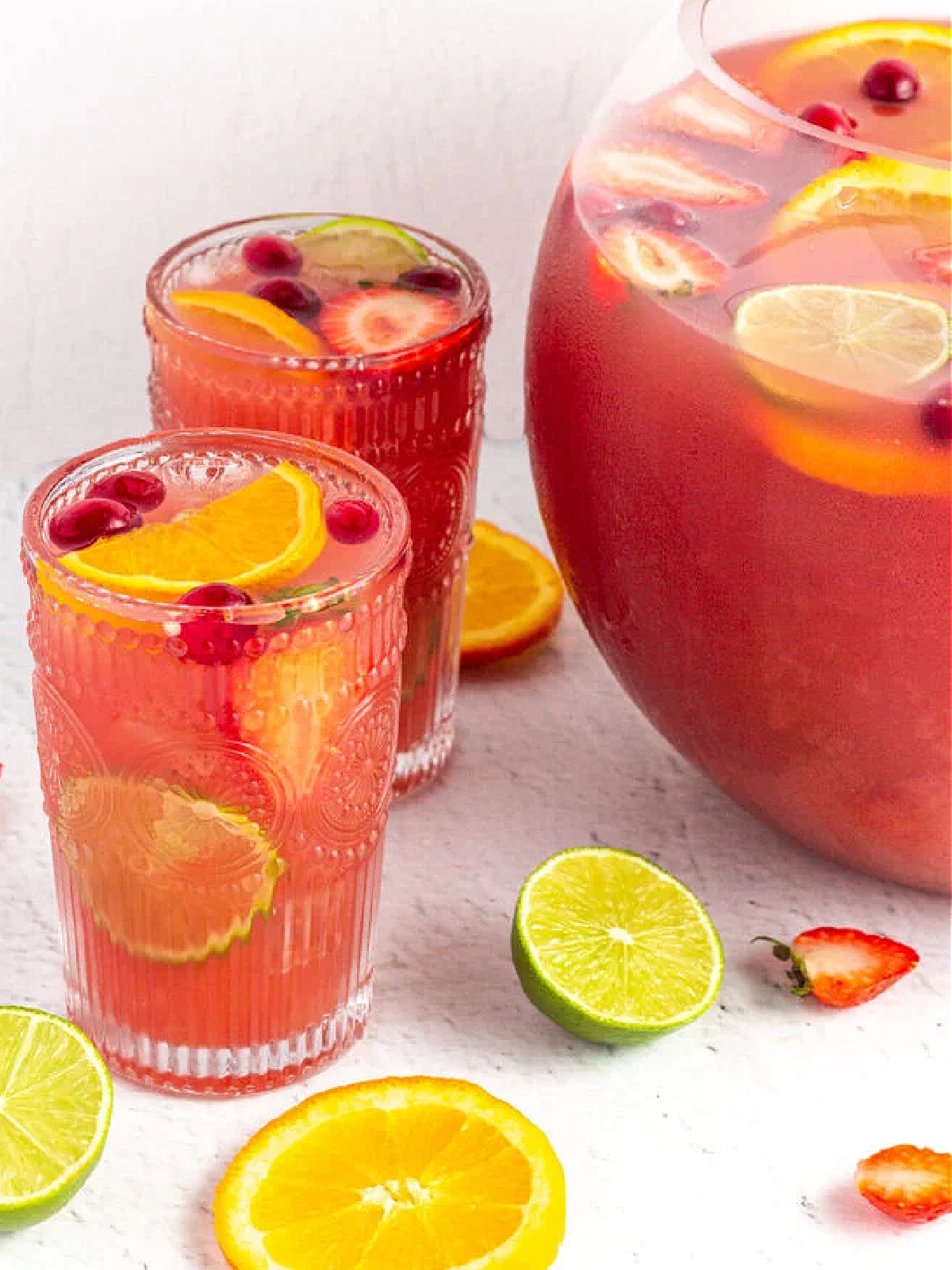 New Years Eve Mocktails- pink punch with sliced fruit like limes and oranges and strawberries -Kids Activities Blog