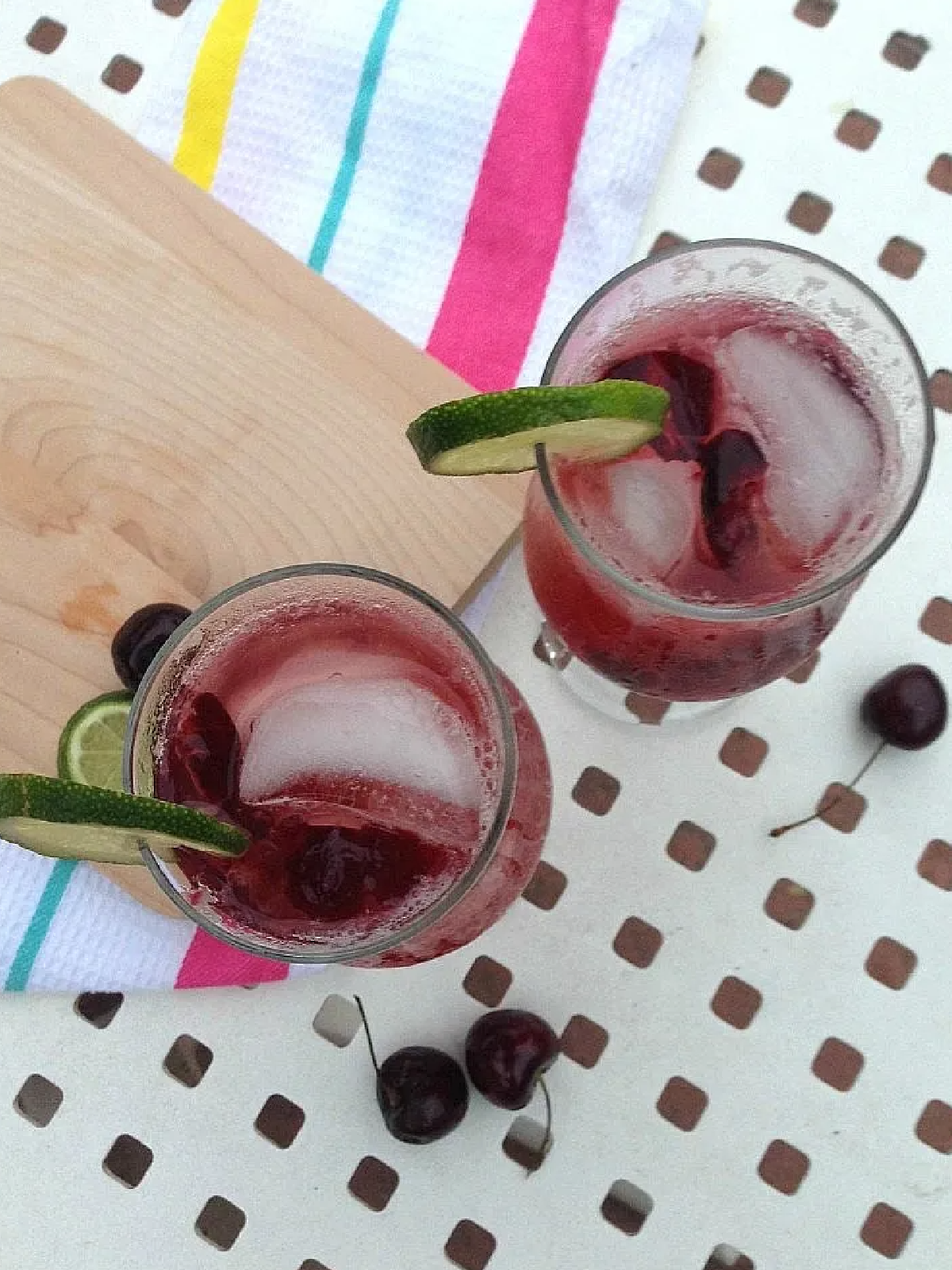 New Years Eve Mocktails- lime and cherries from above on a glass with a pink beverage and ice -Kids Activities Blog
