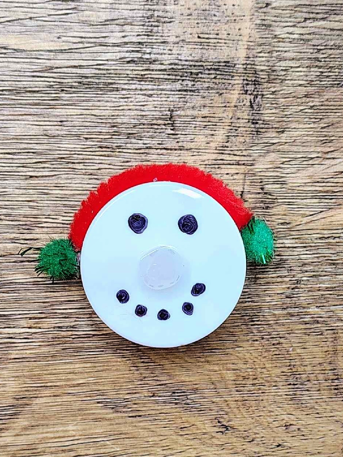 Snowman Craft- Step 4 -Green pom poms glued to the sides of the snowman candle - Kids Activities Blog
