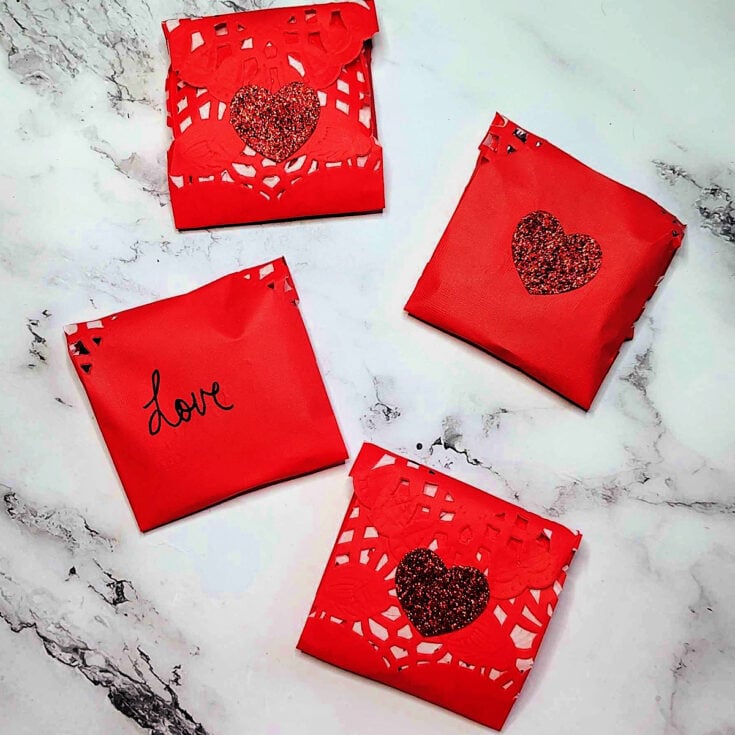 Valentines Envelopes- Finished - 4 envelopes with hearts and text against a marble background- Kids Activities Blog