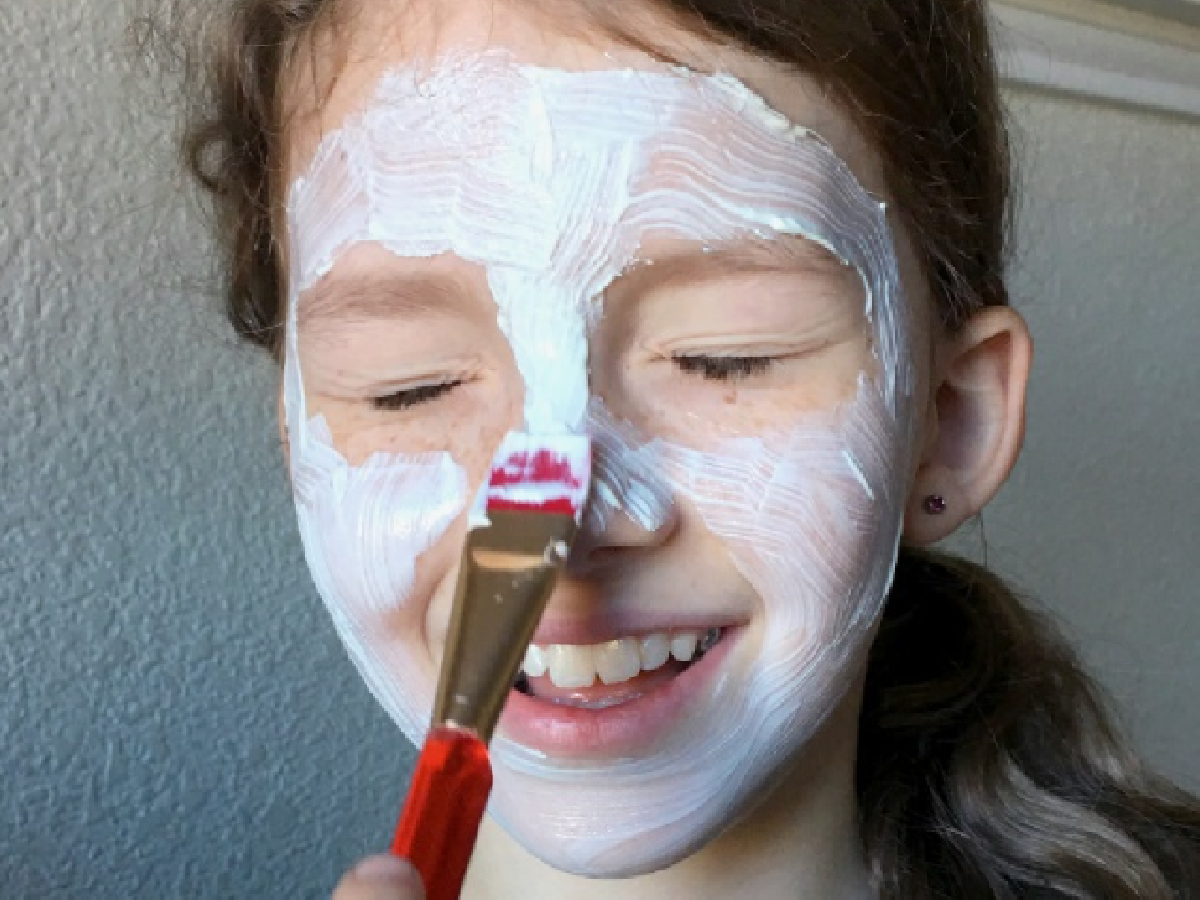 Staycation Ideas- Girl putting face mask on with paint brush- Kids Activities Blog