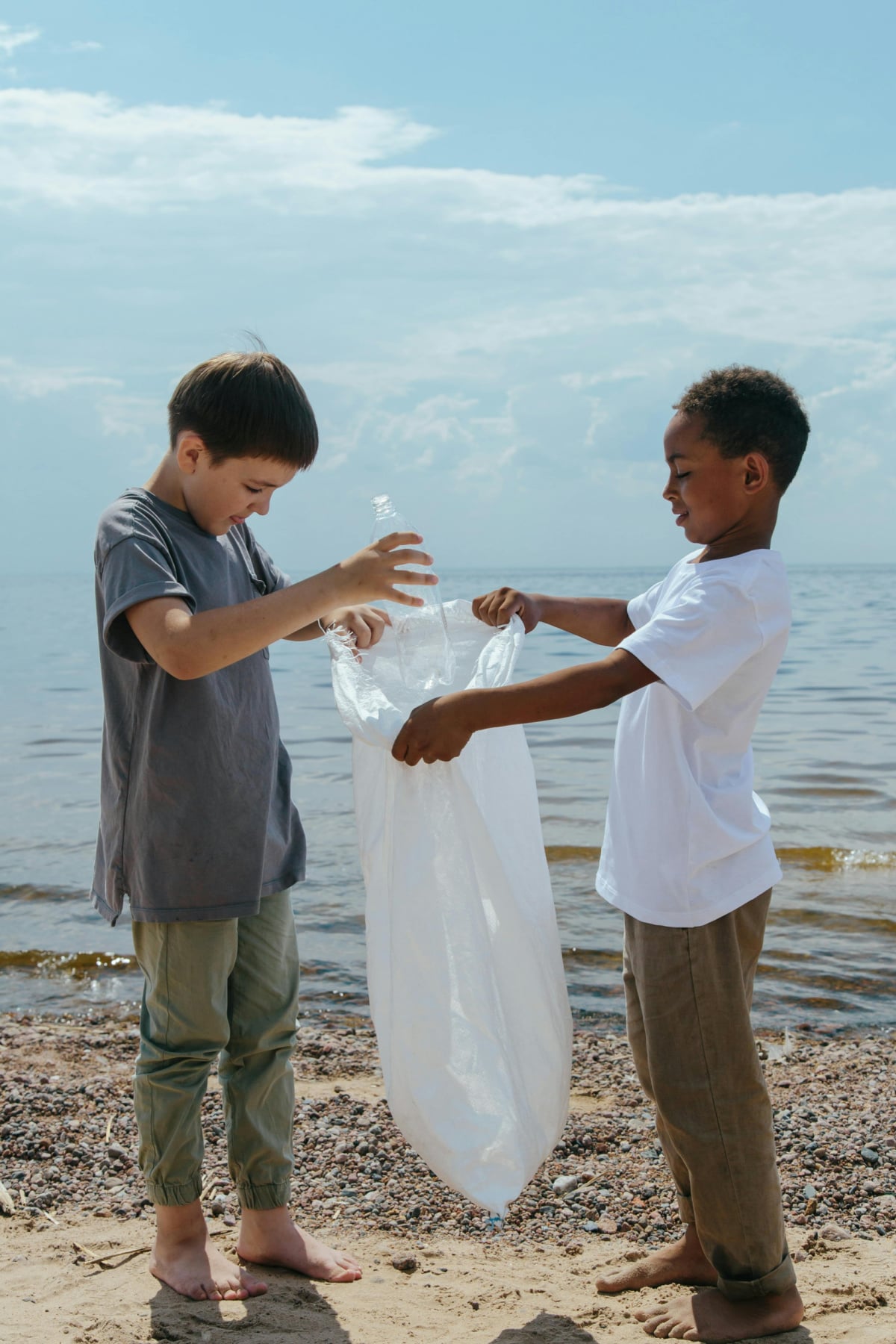 Earth Day Activities- two boys cleaning up trash on the beach- kids activities blog
