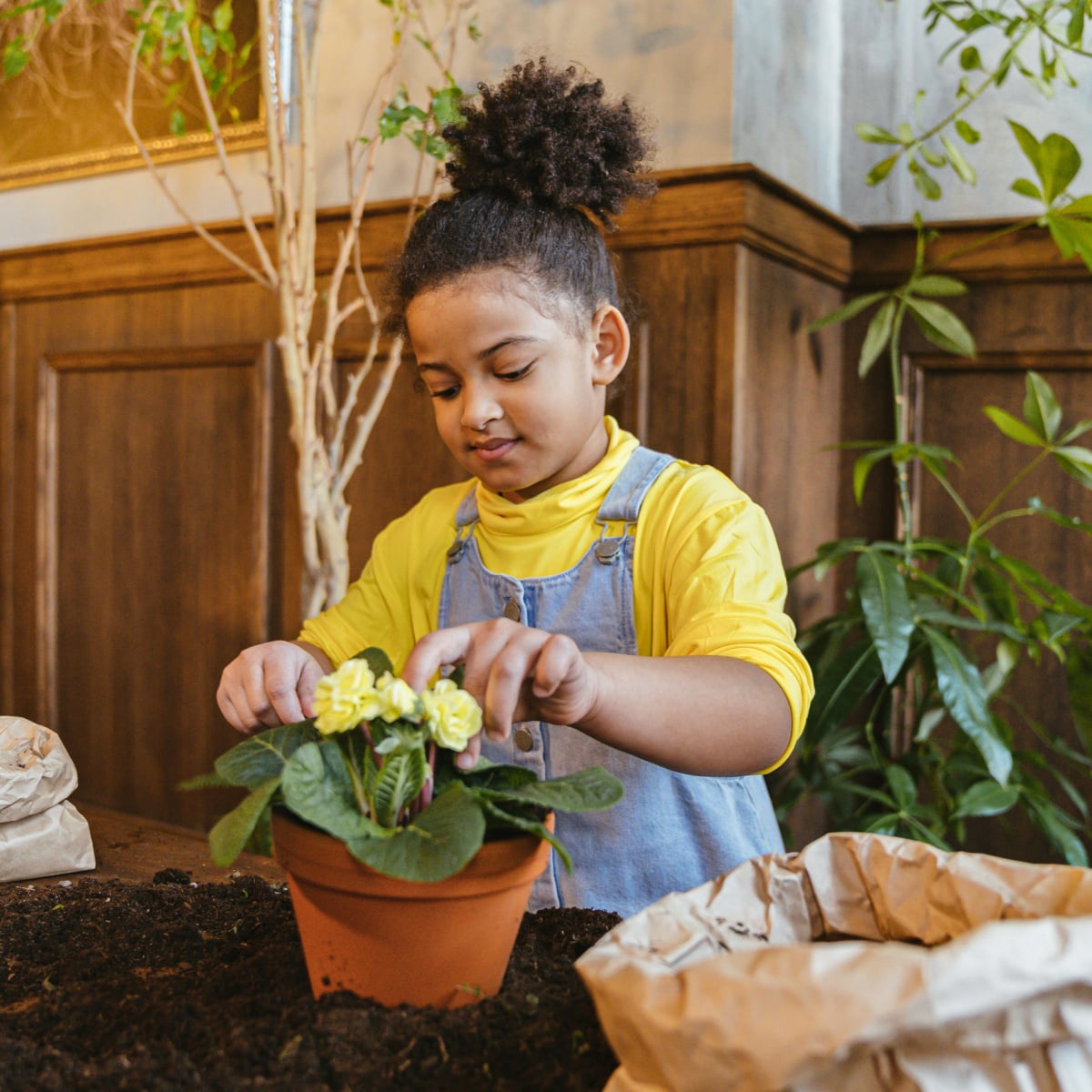 Earth Day Activities- little girl planting flowers in a pot - kids activities blog