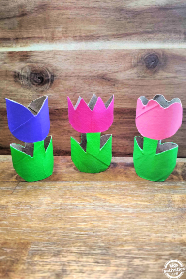 Toilet Paper Roll Spring Craft- purple, dark pink, light pink, green flowers against wood background- Kids Activities Blog
