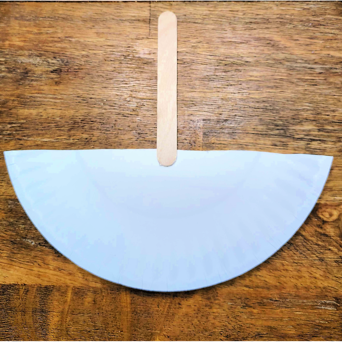 Paper Plate Boat Craft- Step 2 - Glue popsicle stick to paper plate-Kids Activities Blog