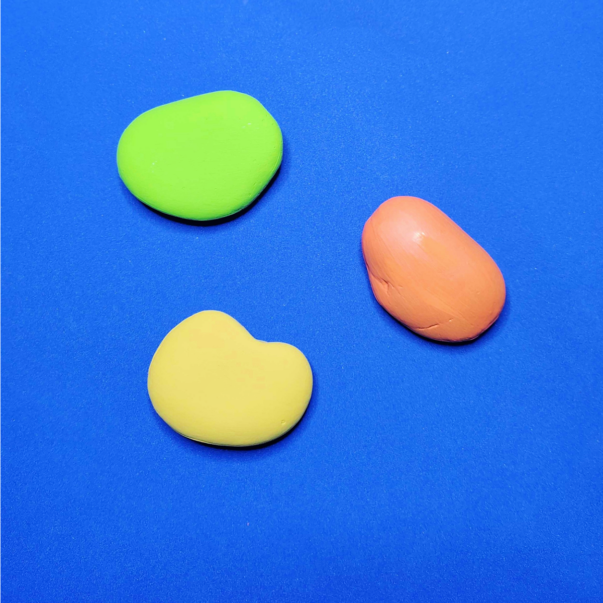 Father's Day Painted Rock Craft- Step 1- Paint rocks orange green and yellow on blue background-Kids Activities Blog