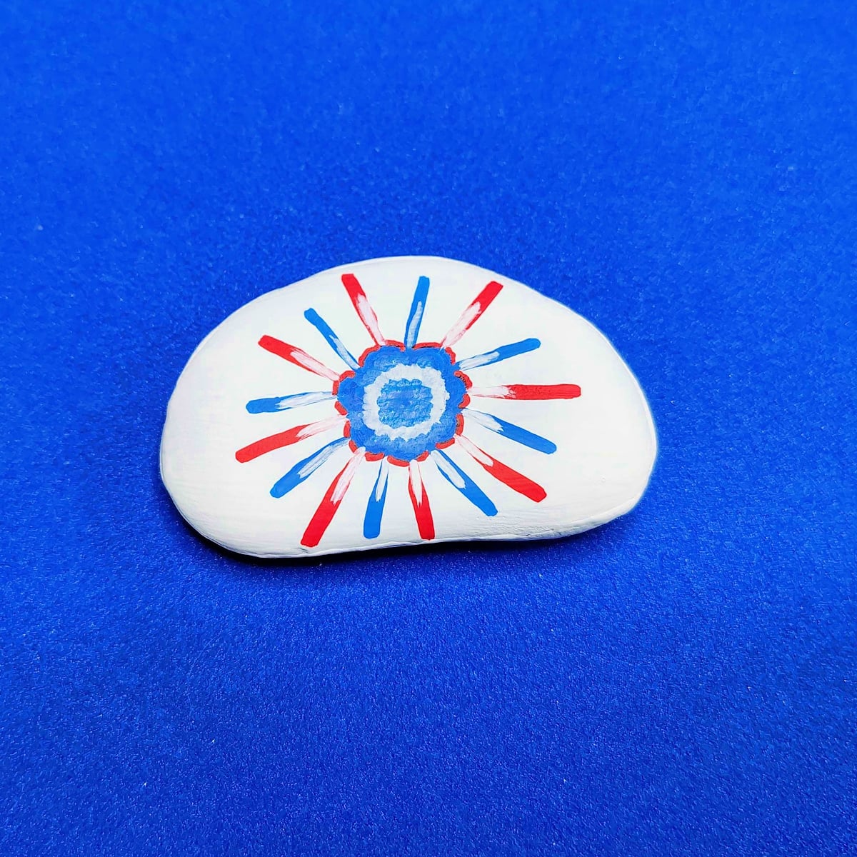 Patriotic Rock Painting Craft- Step 5- Outline blue flower with red, add white to middle of blue flower and at the bottom of the lines -Kids Activities Blog