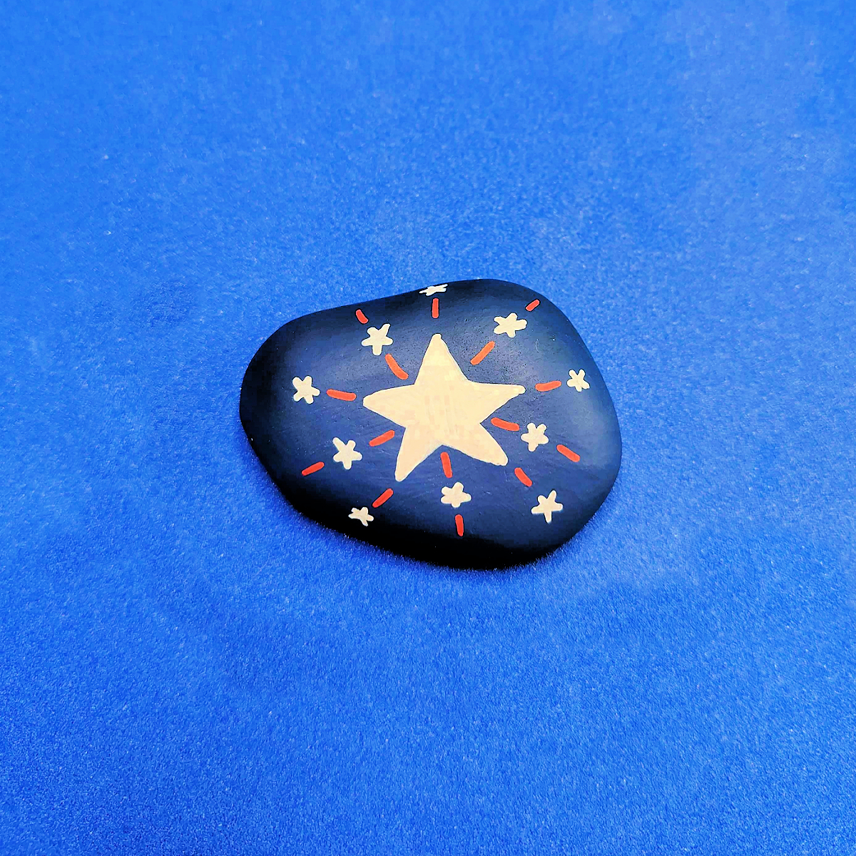 Patriotic Rock Painting Craft- blue rock with white stars and red lines -Kids Activities Blog