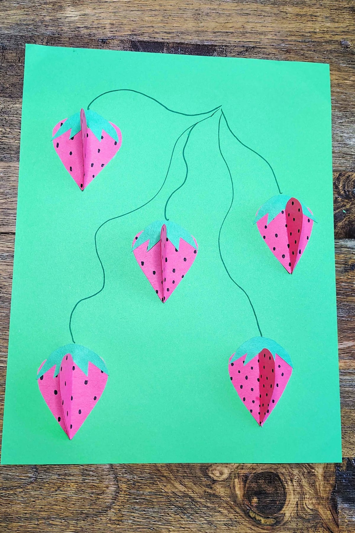 Strawberry Craft- Step 5- Glue strawberries and tops on paper and add vines - Kids Activities Blog
