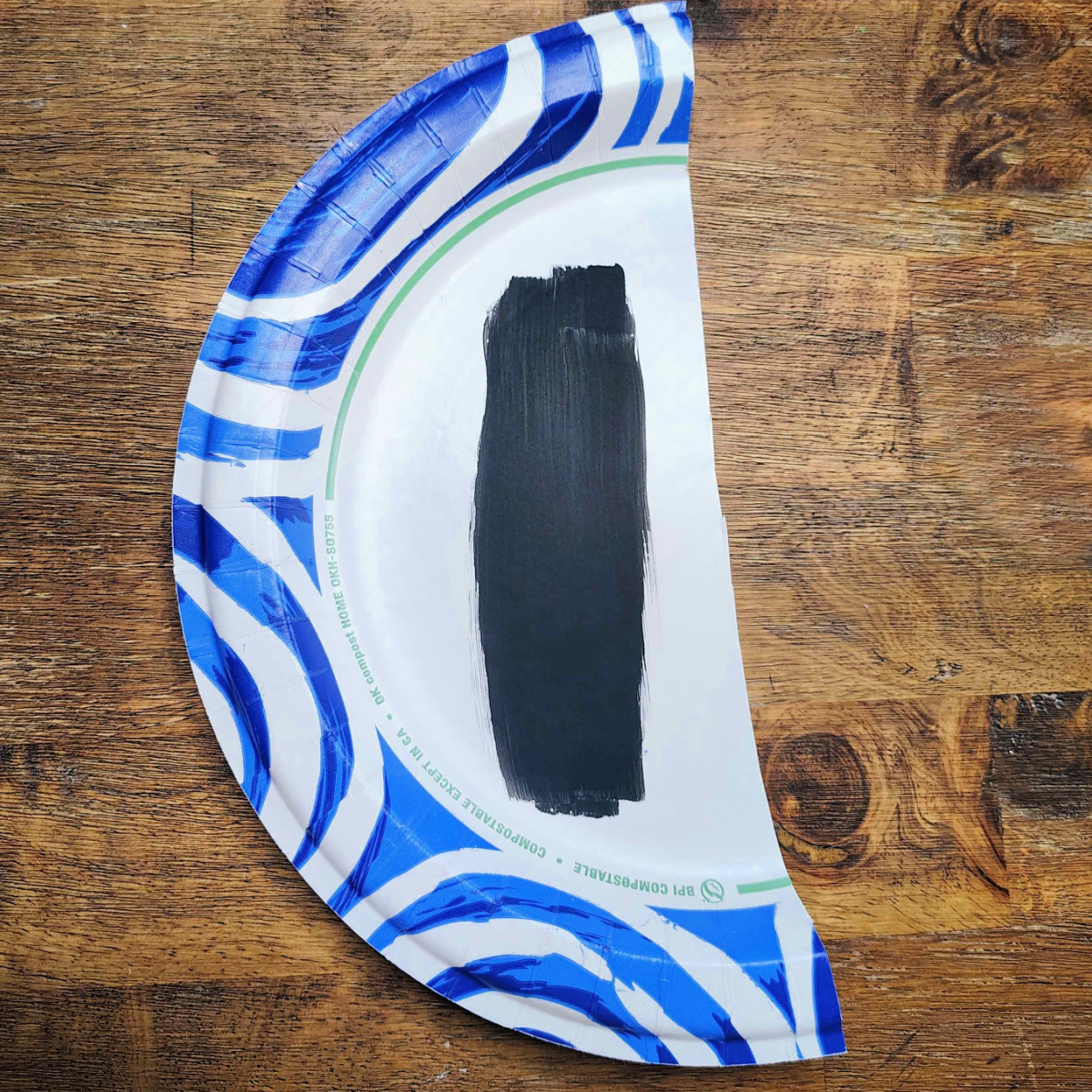 Breakfast Paper Plate Craft- Step 1- Black streak painted on half of a paper plate- Kids Activities Blog